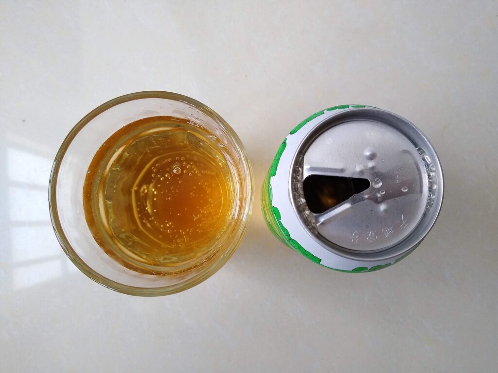 A bottle of pale golden cane vinegar standing next to cut sugarcane on a wooden surface