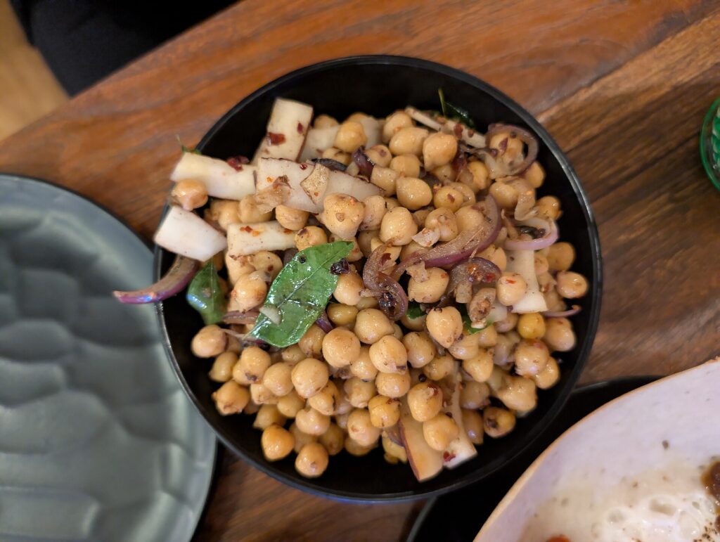 Cooked chickpeas with chopped parsley, cucumber and cherry tomatoes in a shallow bowl