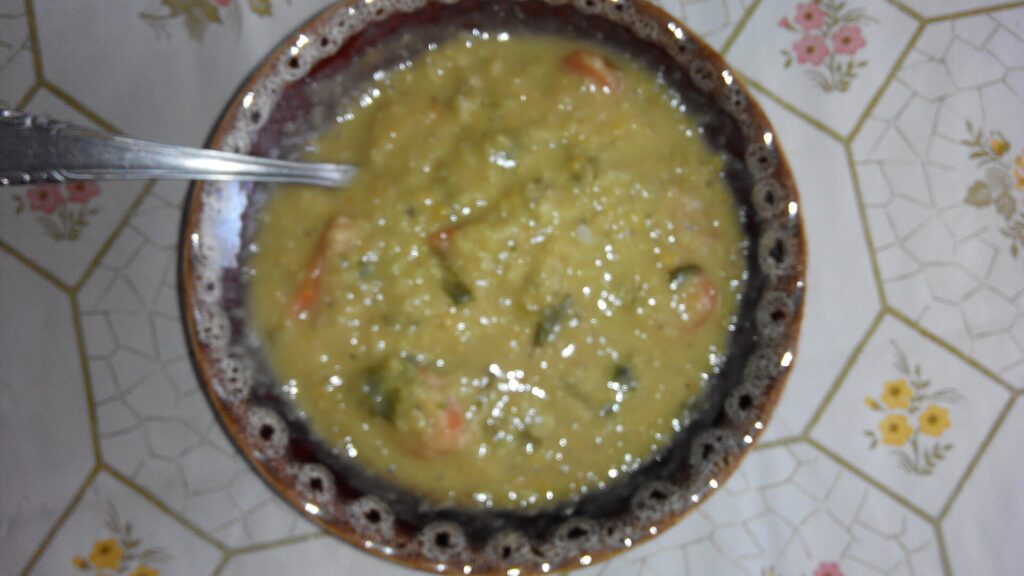 Thick orange lentil soup in a wide bowl with a swirl of yogurt and chopped herbs