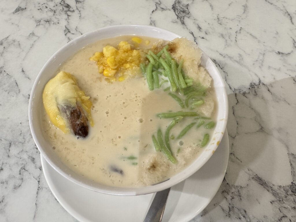 Thick white coconut milk poured into a bowl beside a halved brown coconut shell