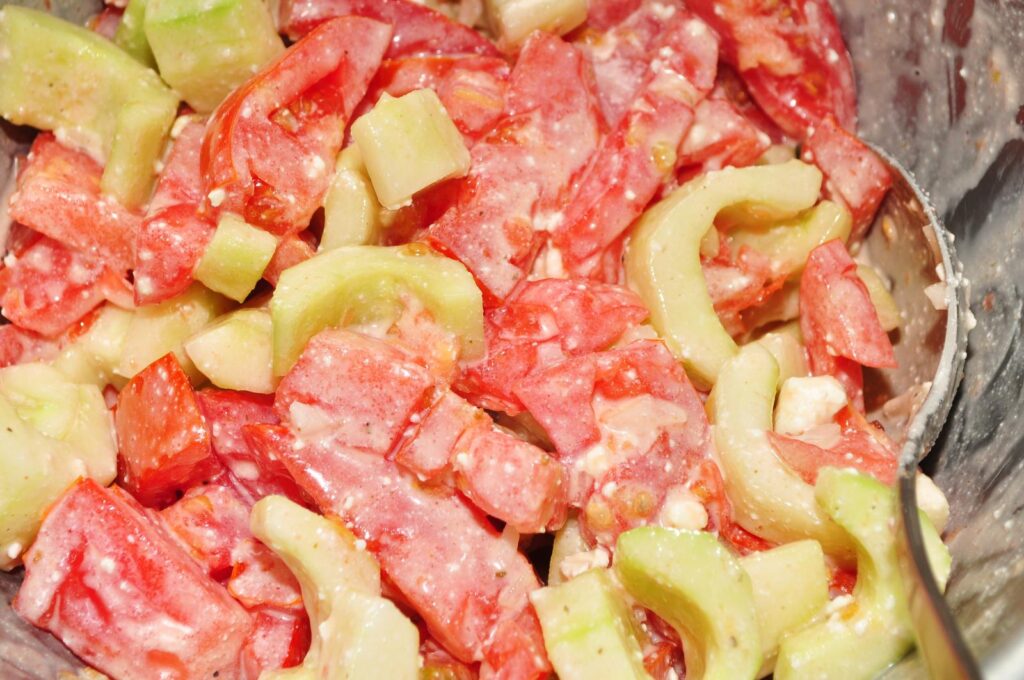 Half-moons of cucumber with red onion, olives and crumbled white cheese in a shallow bowl