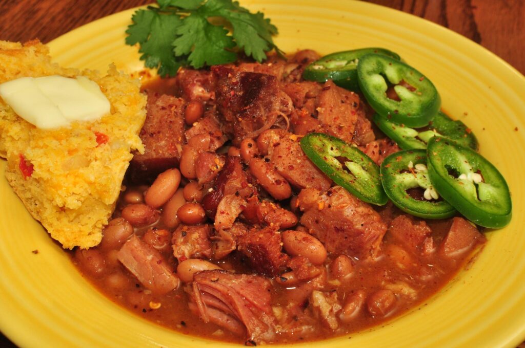 Dark wrinkled smoked chiles sitting in thick red sauce inside an opened tin
