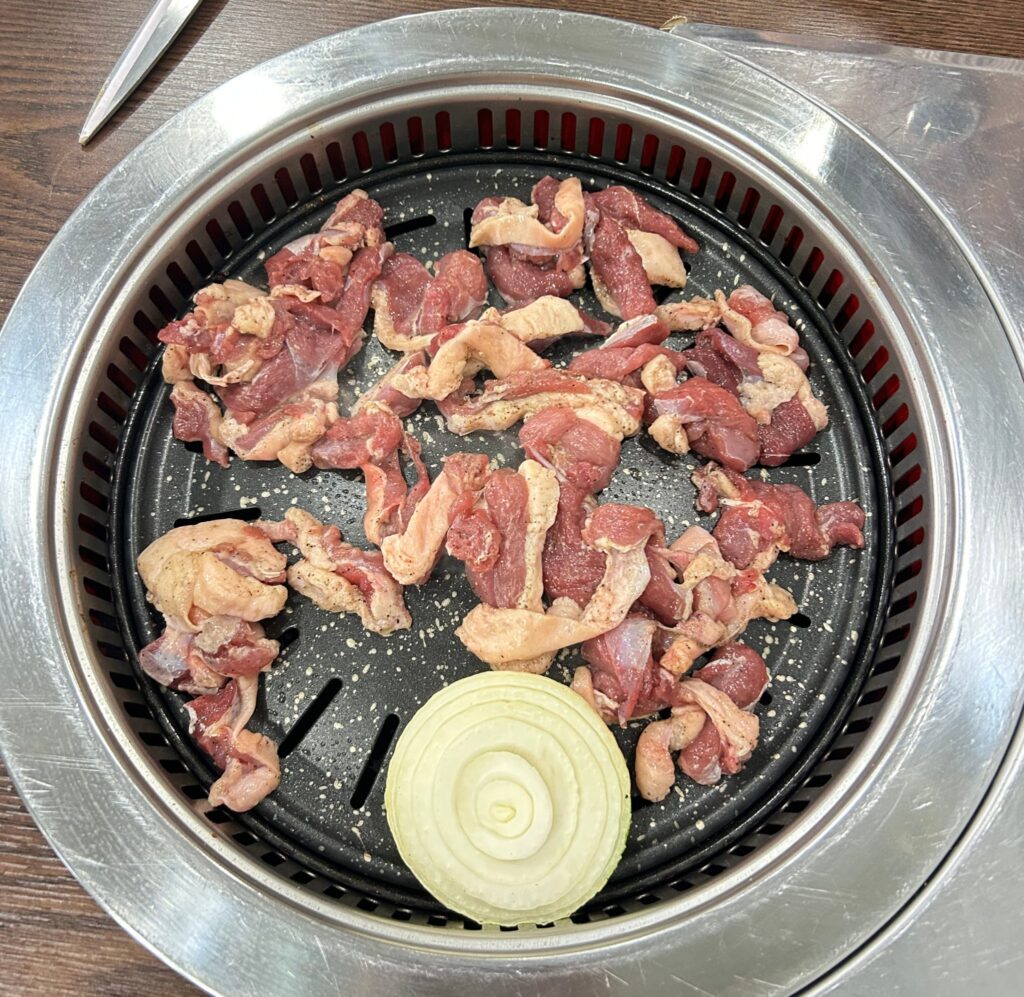 Thin raw slices of beef fanned out on a white platter next to napa cabbage and mushrooms