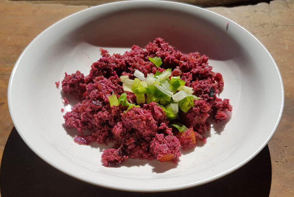 A dense purple-brown block of fermented shrimp paste on a small plate