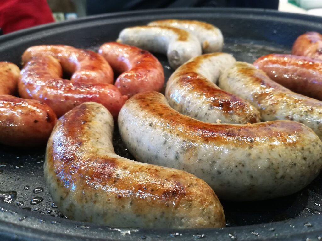 Thick coins of smoked kielbasa sausage on a board next to a piece of slab bacon