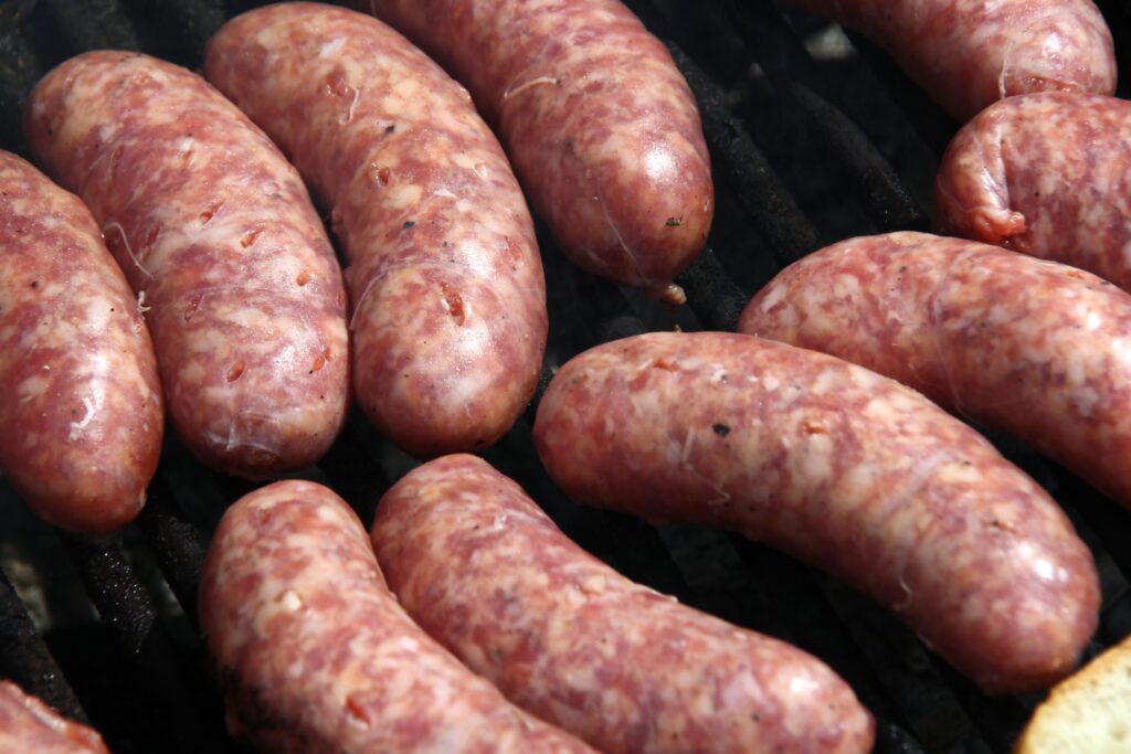 Coiled fresh pork sausages flecked with fennel seed resting on a butcher paper sheet