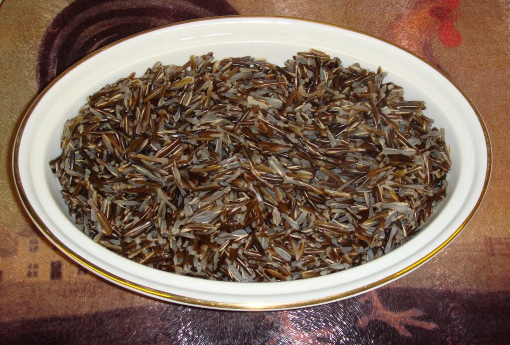A bowl of cooked wild rice with grains split open and curled at the ends