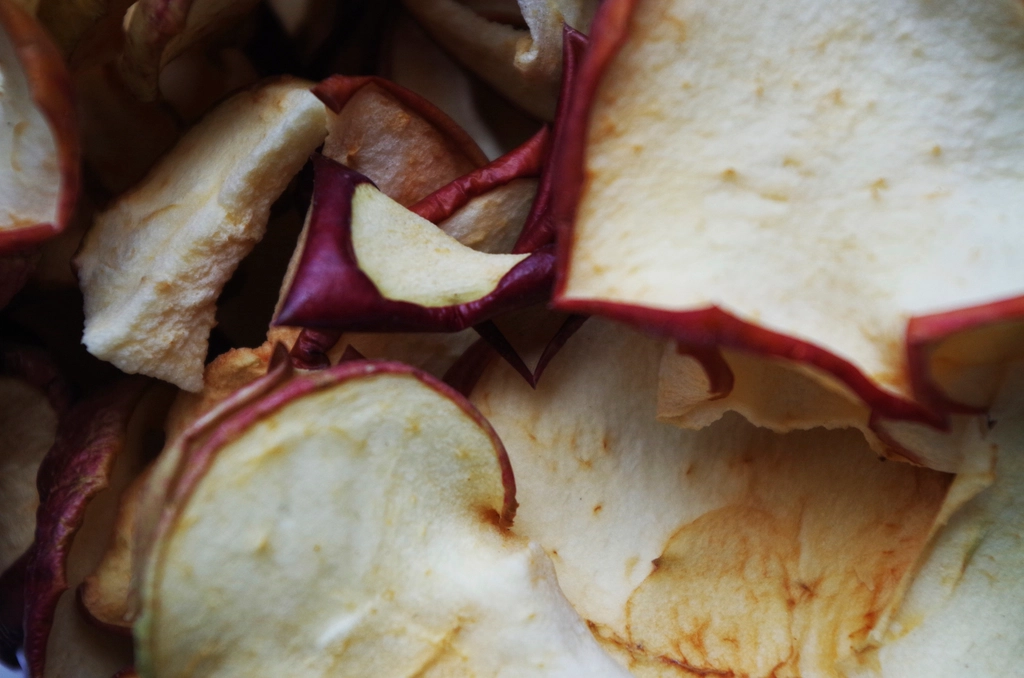 Pale rings of dried apple heaped in a bowl beside a jar of amber syrup