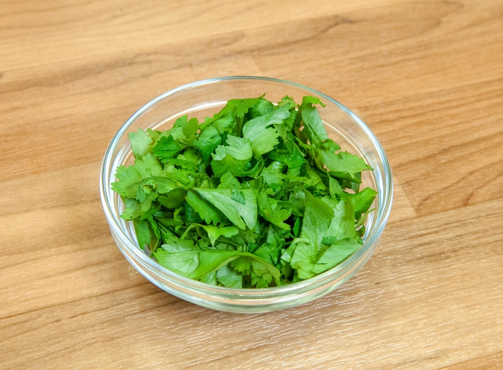 Large bunches of flat parsley and cilantro tied together on a wooden board