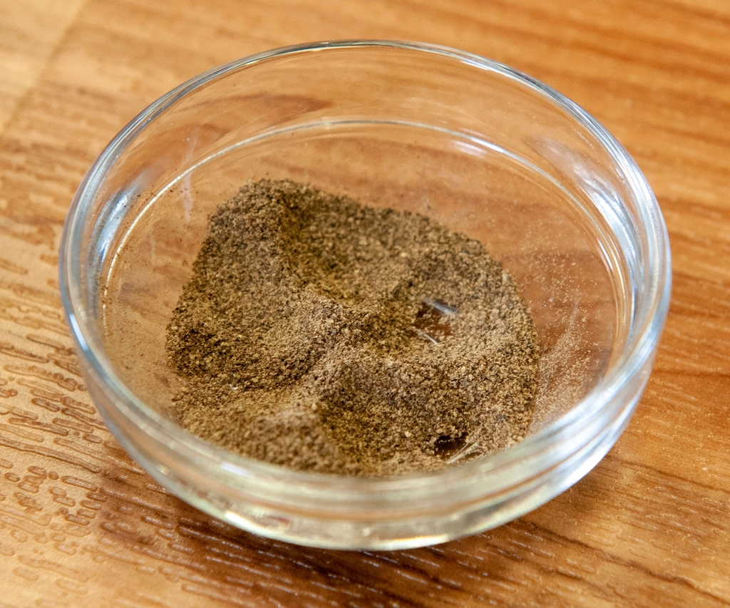 Small heaps of cumin, coriander, paprika and turmeric measured out on a dark surface
